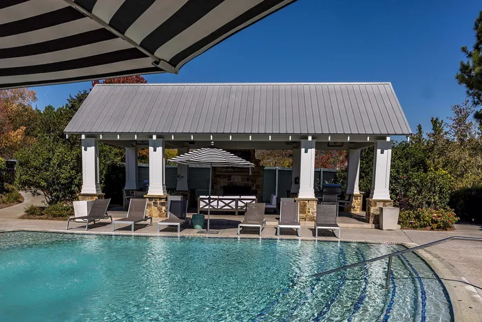 Outdoor pool on a sunny day with pool chairs and umbrella