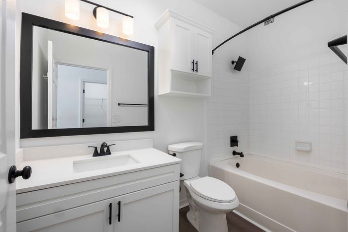 Bathroom with standard tub and sink with large mirror above the mirror