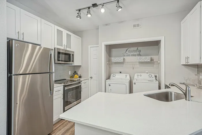 Kitchen with white cabinets and counters and stainless steel appliances