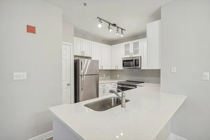 Kitchen with white cabinets and counters and stainless steel appliances