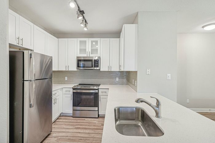 Kitchen with white cabinets and counters and stainless steel appliances