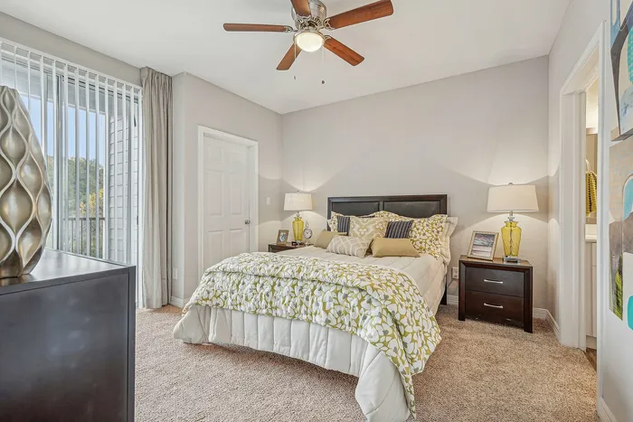 Furnished bedroom with lighted ceiling fan and bed with bedside tables