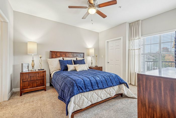 Furnished bedroom with lighted ceiling fan and bed with bedside tables