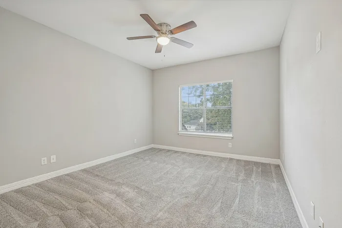 Unfurnished bedroom with carpet and lighted ceiling fan and carpet