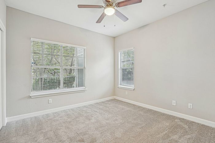 Unfurnished bedroom with carpet and lighted ceiling fan and carpet