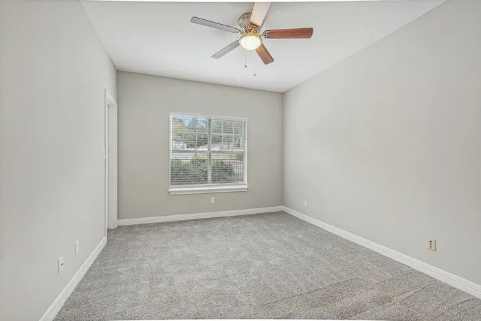 Unfurnished bedroom with carpet and lighted ceiling fan and carpet
