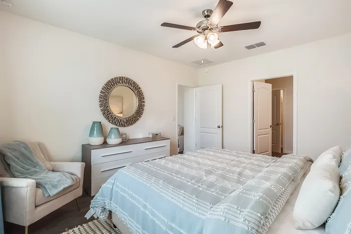 Inviting bedroom with plush beige chair, modern dresser, and stylish decor elements.