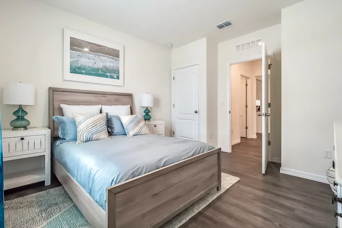 Fairview, NC, Single Family Homes for Rent with In-Unit Washer and Dryer - Fairview Meadows - Bedroom with Wood-Inspired Plank Flooring, Area Rug, Bed with Wooden Frame, Nightstands with Lamps, and Wall Art.