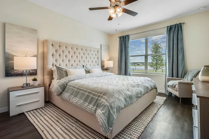 Townhomes Near The Biltmore in Fairview, NC - Fairview Meadows - Bedroom Featuring Large Window w/ Blinds, Blue Curtains, Wood-Style Flooring, and Ceiling Fan