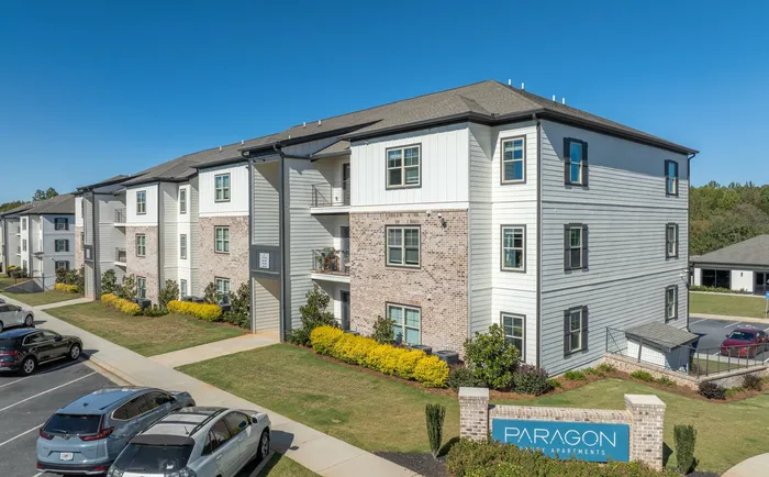 Modern apartment complex with lush landscaping and ample parking.