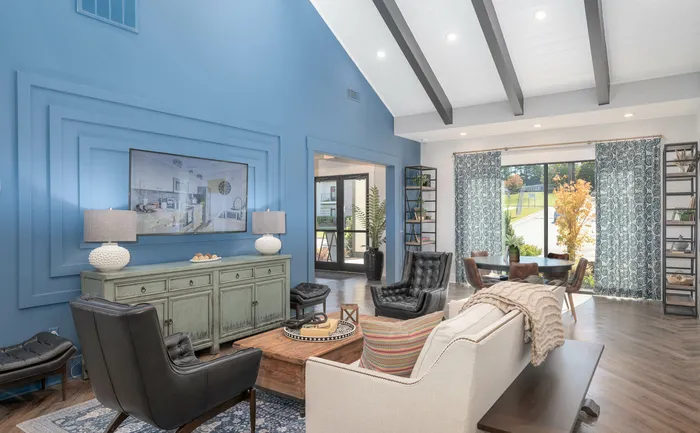 Elegant clubroom with blue accent wall, stylish furnishings, and large windows.