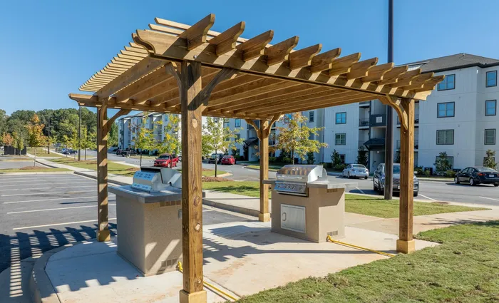 Outdoor grill area with wooden pergola at modern apartment complex