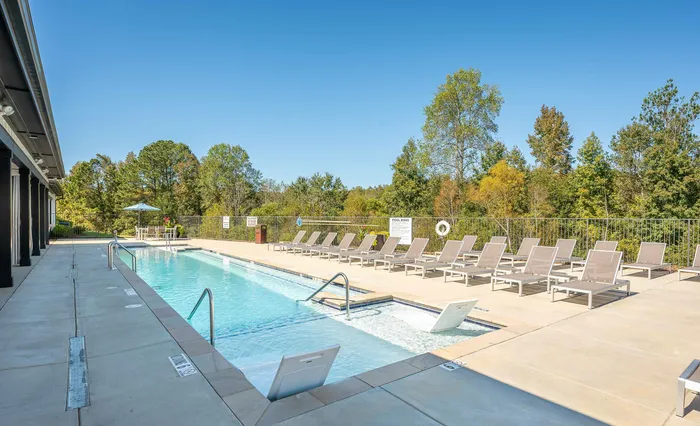 Inviting outdoor pool with sun loungers and lush greenery, serene relaxation