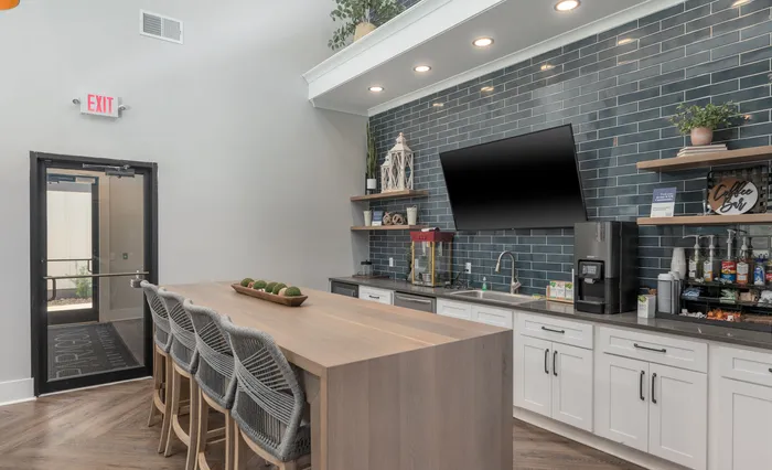 Sleek entertaining kitchen in clubroom with elegant rattan chairs and modern amenities