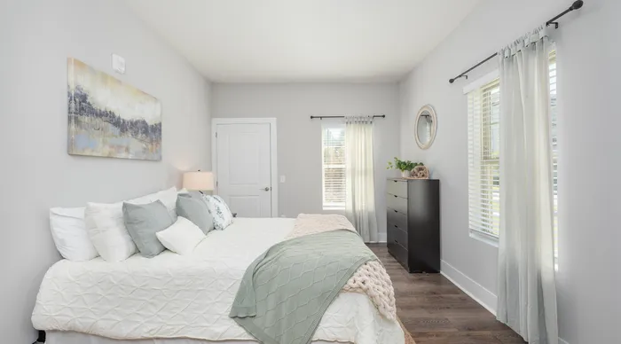 Bright and airy bedroom with elegant decor, featuring a comfortable bed, soothing color palette, large windows with soft curtains, and stylish furnishings.