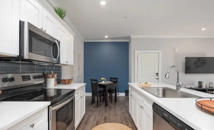 Elegant modern kitchen with white cabinetry, stainless steel appliances, and cozy dining area.
