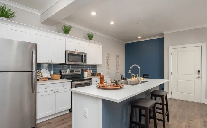 Stunning modern kitchen with sleek stainless steel appliances, elegant white cabinetry, and a contemporary island with seating.