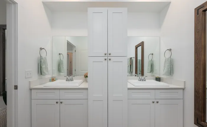 Modern dual vanity bathroom with white cabinets, large mirrors, and sleek fixtures.