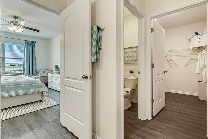 Inviting bedroom with large window, modern ceiling fan, and luxurious bedding.