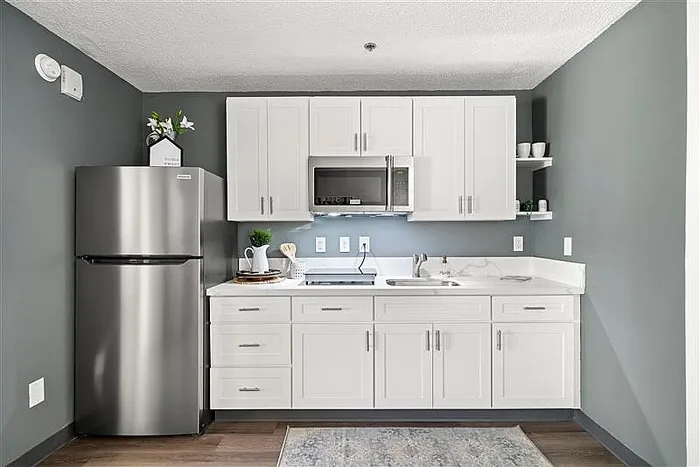 3-BR Apartments In Raleigh, NC - 1105 Flats North Hills - A Modern, Compact Kitchen With White Shaker Cabinets, Slate Grey Walls, And Stainless Steel Appliances.