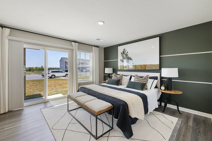 Furnihsed primary bedroom with bedside tables and sliding glass doors