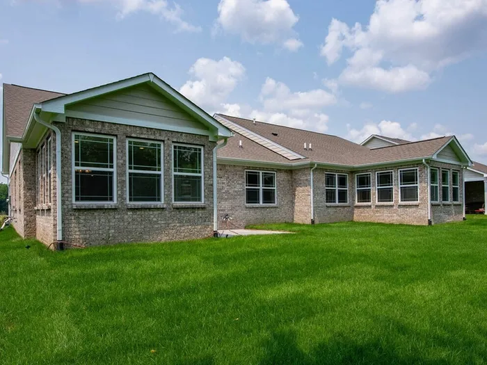 Pet-Friendly Homes for Rent in Avon, IN - Woods at Countryside Crossing - Exterior View Of Back Of Home With Beige Brick And A Lush Lawn