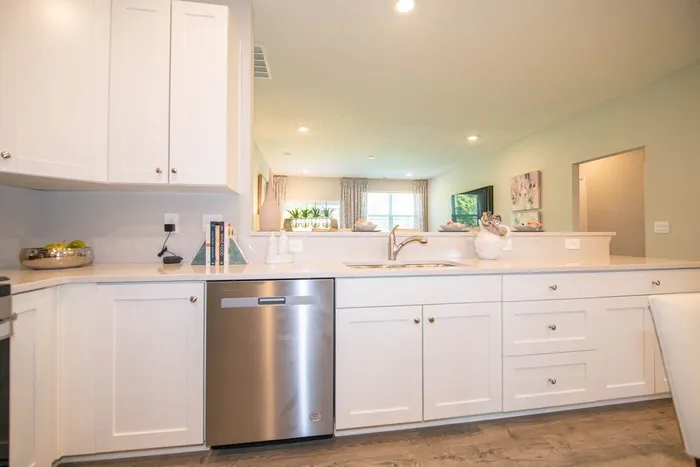Kitchen with stainless steel dishwasher and sink and white cabinets