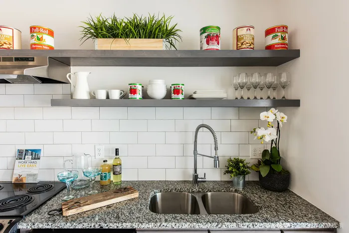 close up of kitchen sink with gooseneck faucet and open shelving above