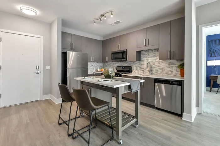 Sandy Springs, GA, Luxury Apartments Near Atlanta - The Morgan Sandy Springs - Kitchen with a Movable Island, Quartz Countertops, Tile Backsplash, and Stainless Steel Appliances.