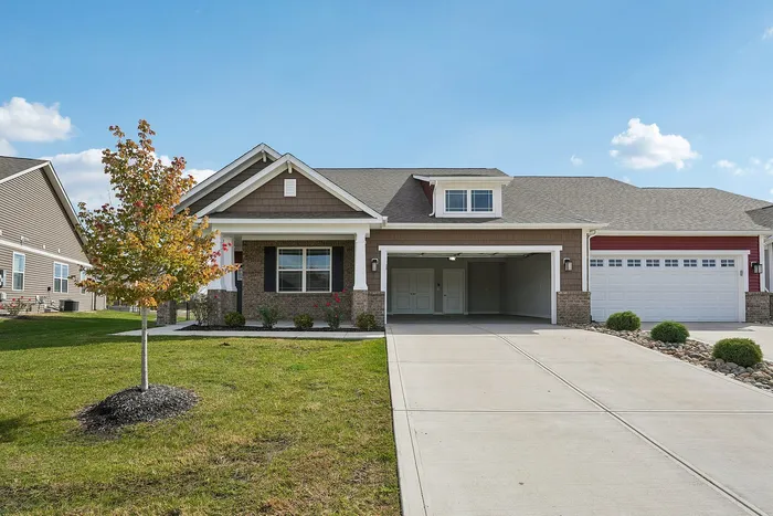Dog-Friendly Homes for Rent in Whitestown, IN - Prairie Chase - Attached Garage Of A Single-Story Home, With A Driveway, Well-Maintained Lawn, And A Tree.