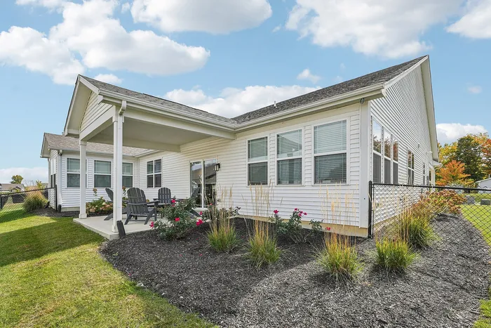 2-BR Homes in Whitestown, IN - Prairie Chase - A Covered Patio With Patio Chairs, Table, Lush Landscaping, And A Metal Railing.
