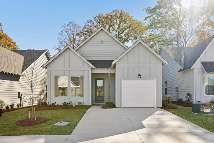 Opelika, AL Homes for Rent - Champions Square - Exterior of a Home with Attached Garage, Driveway, Manicured Grass Lawn, Flowering Plants, and Trees.