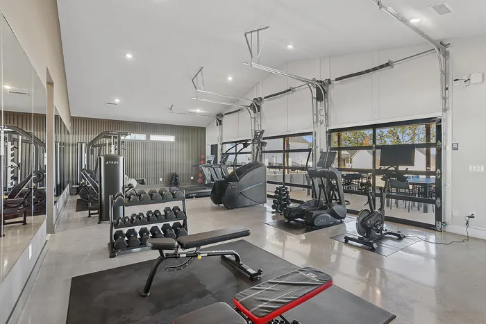 3-Bedroom Homes for Rent in Opelika, AL - Champions Square - Spacious Fitness Center With Cardio Machines, Free Weights, Workout Bench, And Large Glass Garage Door Opening To Patio Seating.