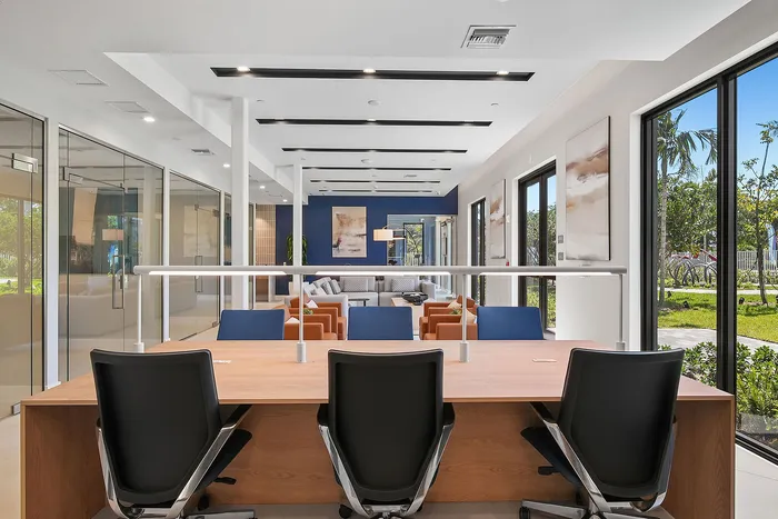 Modern open concept office space with stylish seating, large windows offering lush garden views, and sleek conference rooms for optimal productivity.