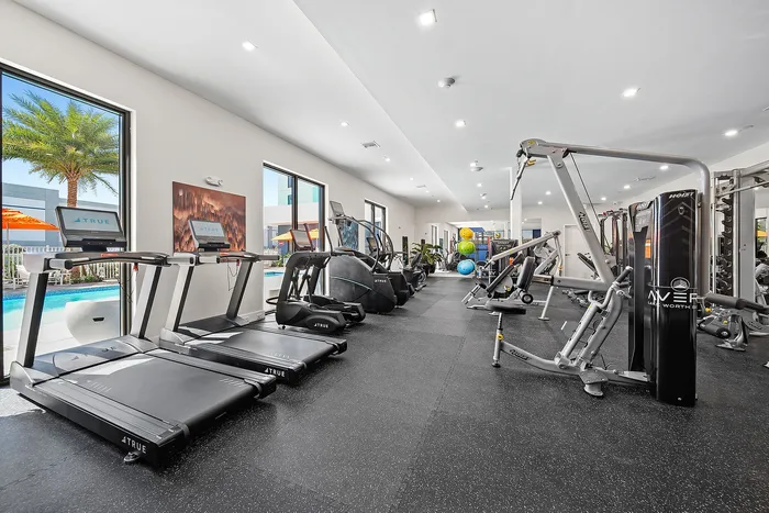 Modern fitness center with state-of-the-art gym equipment and pool views, ideal for a healthy lifestyle.