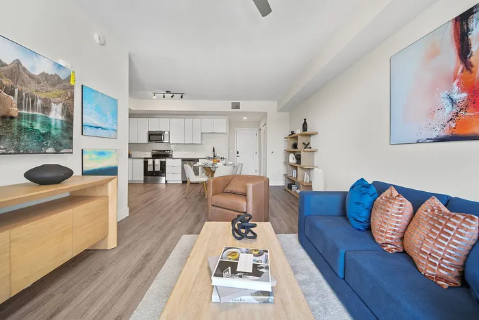 Modern open-concept living space featuring a sleek kitchen, cozy seating area, stylish decor, and vibrant artwork.