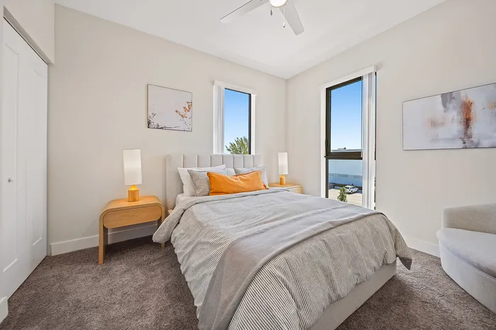 Bright and airy bedroom with large windows, modern decor, and soothing neutral tones, offering a serene and inviting atmosphere.