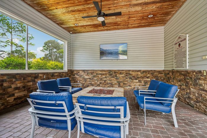 Charming patio with cozy blue seating, stone accent walls, and a fire pit for outdoor relaxation.