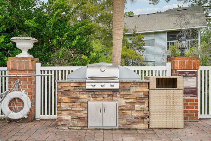 Inviting outdoor grilling area with a sleek stainless steel barbecue set against a stylish stone counter, perfect for entertaining in a lush garden setting.