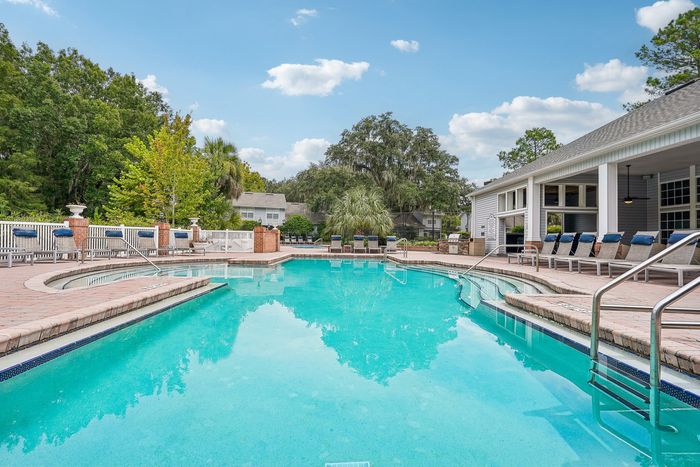 Charming outdoor pool area with crystal clear water, surrounded by lush greenery and inviting lounge chairs, perfect for relaxation and leisure.