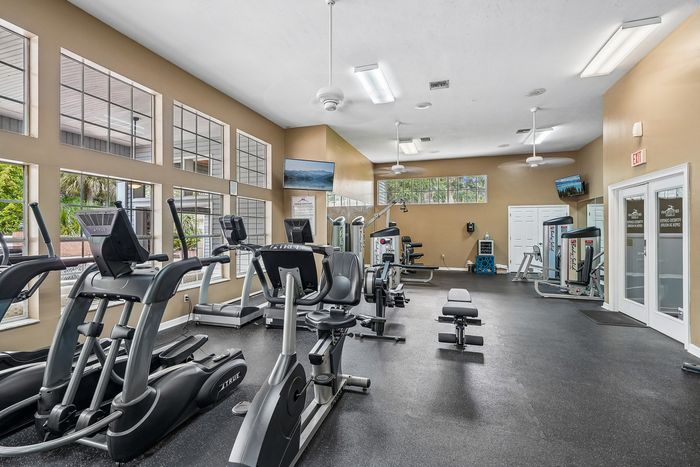 Bright and spacious fitness center with modern exercise equipment, large windows, and high ceilings.