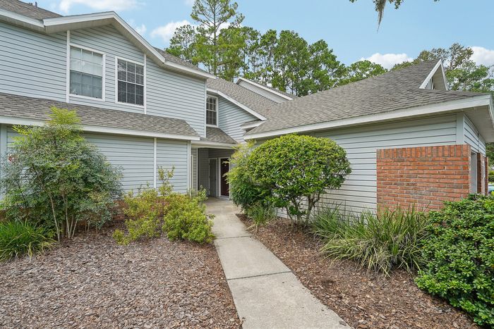 Charming townhouse with a classic design and lush landscaping, offering a welcoming entrance and abundant greenery.