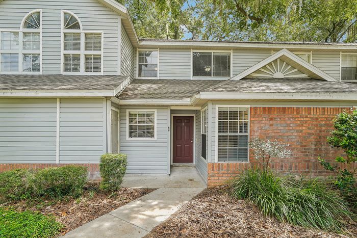 Charming townhouse with a welcoming entrance, large windows, and a blend of brick and siding for modern appeal.