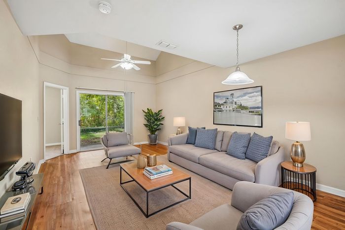 Bright and inviting living room with plush sofas, modern decor, and a scenic view through large sliding glass doors.
