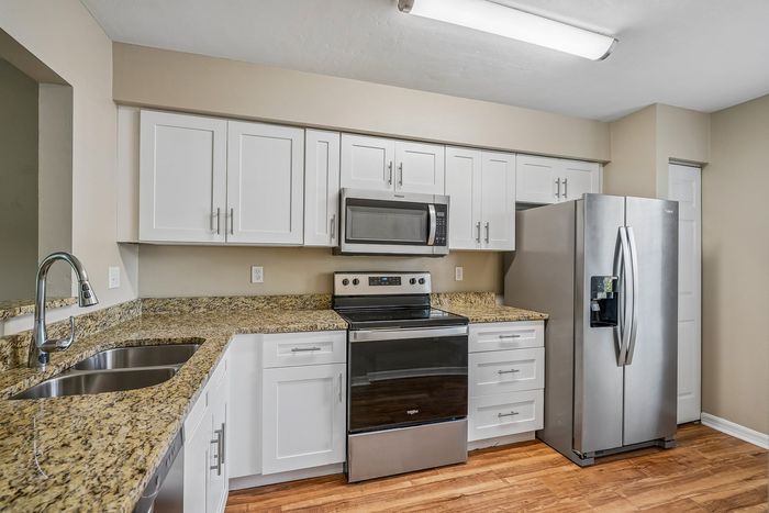 Modern kitchen featuring sleek stainless steel appliances, elegant granite countertops, and crisp white cabinetry for a stylish cooking space.