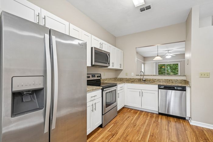 Modern kitchen with sleek stainless steel appliances, elegant granite countertops, and pristine white cabinetry offering a bright and inviting atmosphere.