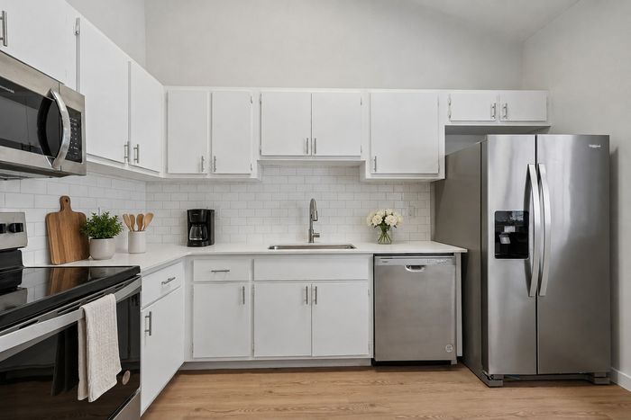 Modern kitchen with sleek white cabinets, stainless steel appliances, and elegant subway tile backsplash.