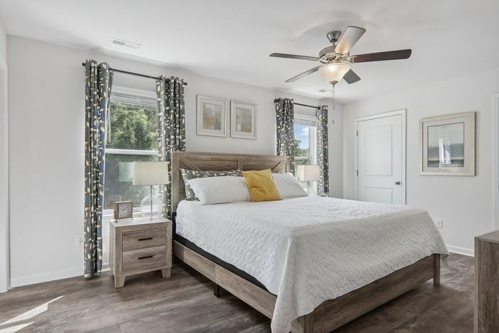 Bright and inviting bedroom with elegant decor, large windows, and a stylish ceiling fan.
