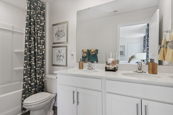 Bright, modern bathroom featuring elegant double sinks, a stylish shower curtain, and tasteful wall art, perfect for a luxurious living space.
