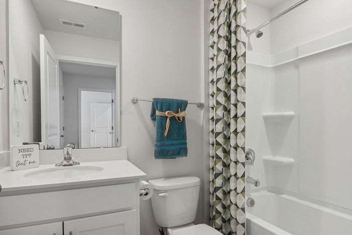 Bright and modern bathroom featuring sleek white cabinetry, an elegant mirror, and a stylish patterned shower curtain.
